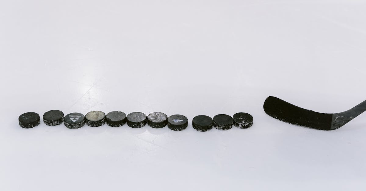 A row of hockey pucks and a stick on an ice rink, perfect for sports content.